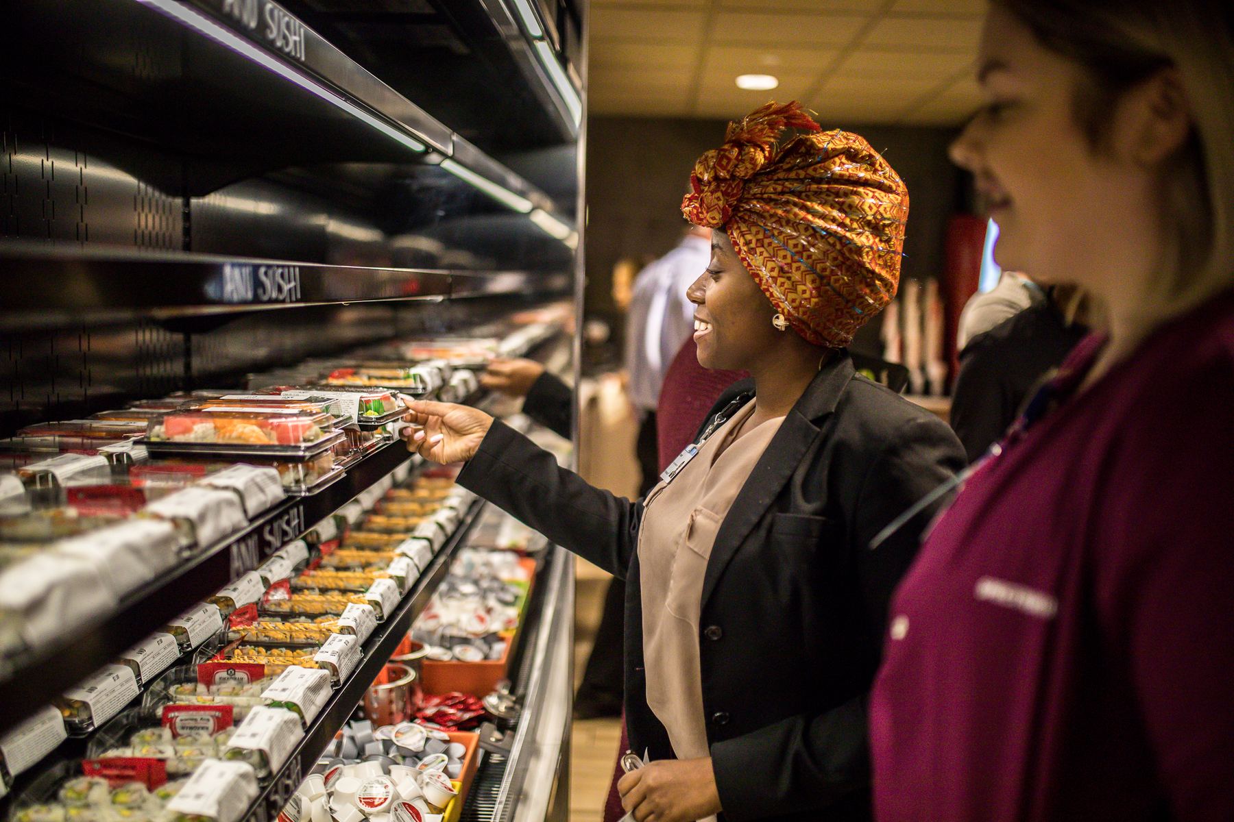 A guest choosing a fresh Anu Sushi roll from a grab-and-go case